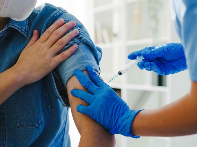 A nurse injects vaccine into a patient.
